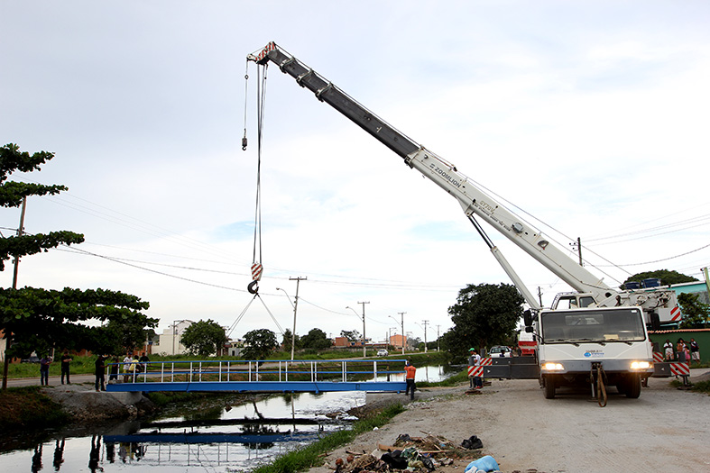 um caminhão guindaste colocando uma ponte de ferro
