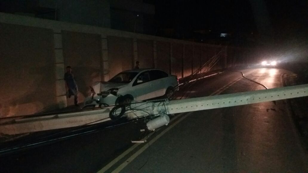 um carro batido em um muro e um poste no chão