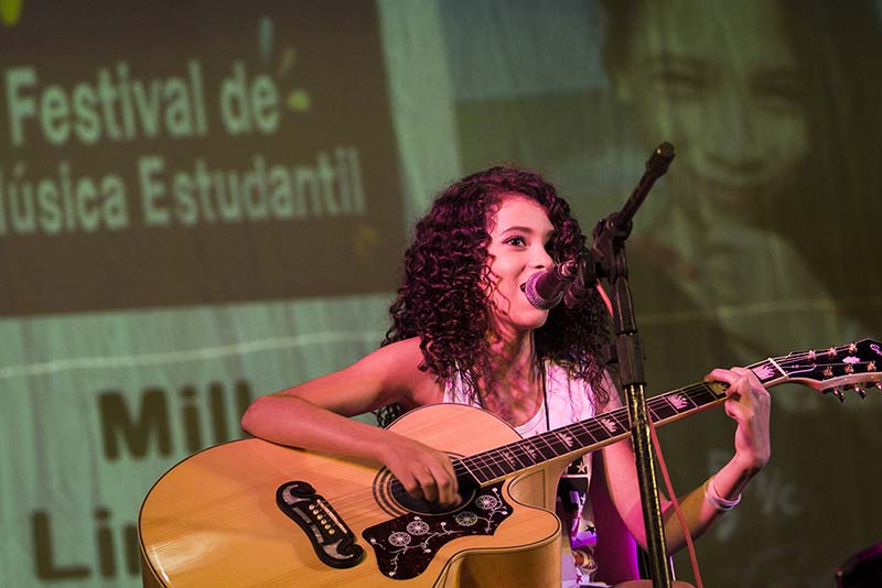 Foto de mulher cantando e tocando violão