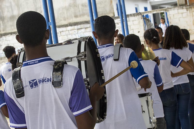 Foto de alunos uniformizados com instrumentos musicais